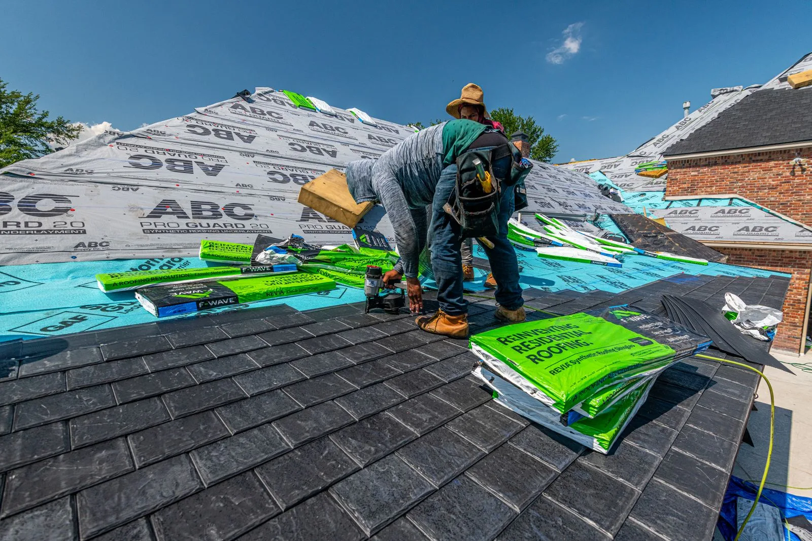 Roofers fitting new shingles on a brick house roof