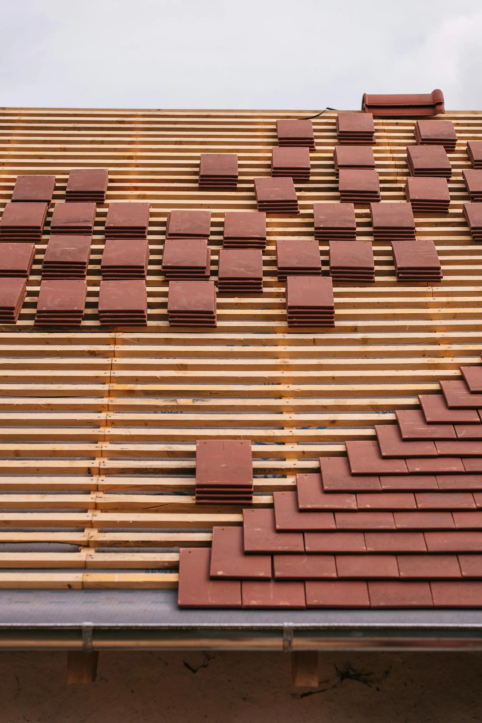 Roofers installing red clay tile on a new Florida roof